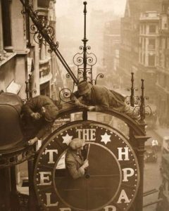 Workmen dismantle the clock that hangs outside the Daily Telegraph offices. The building is due to be remodeled. London, 1930